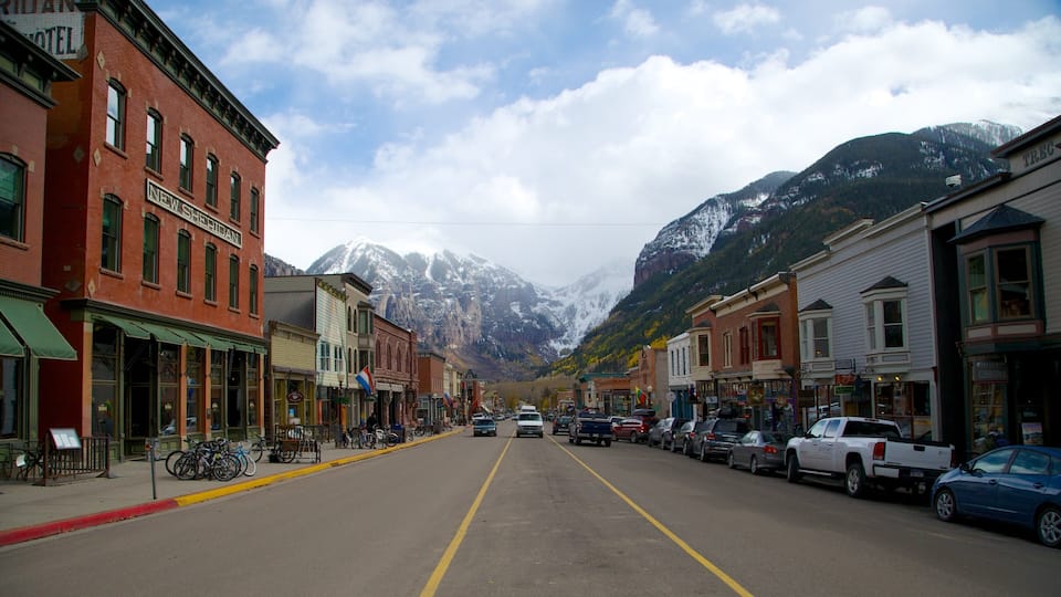 A street lined with historic buildings, a mountain range in the background, and a clear sky.