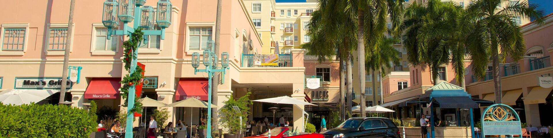 A sunny street with palm trees, a red car, and a building with a sign that says "Max's Grill".