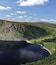 A lake surrounded by green hills and a clear sky.