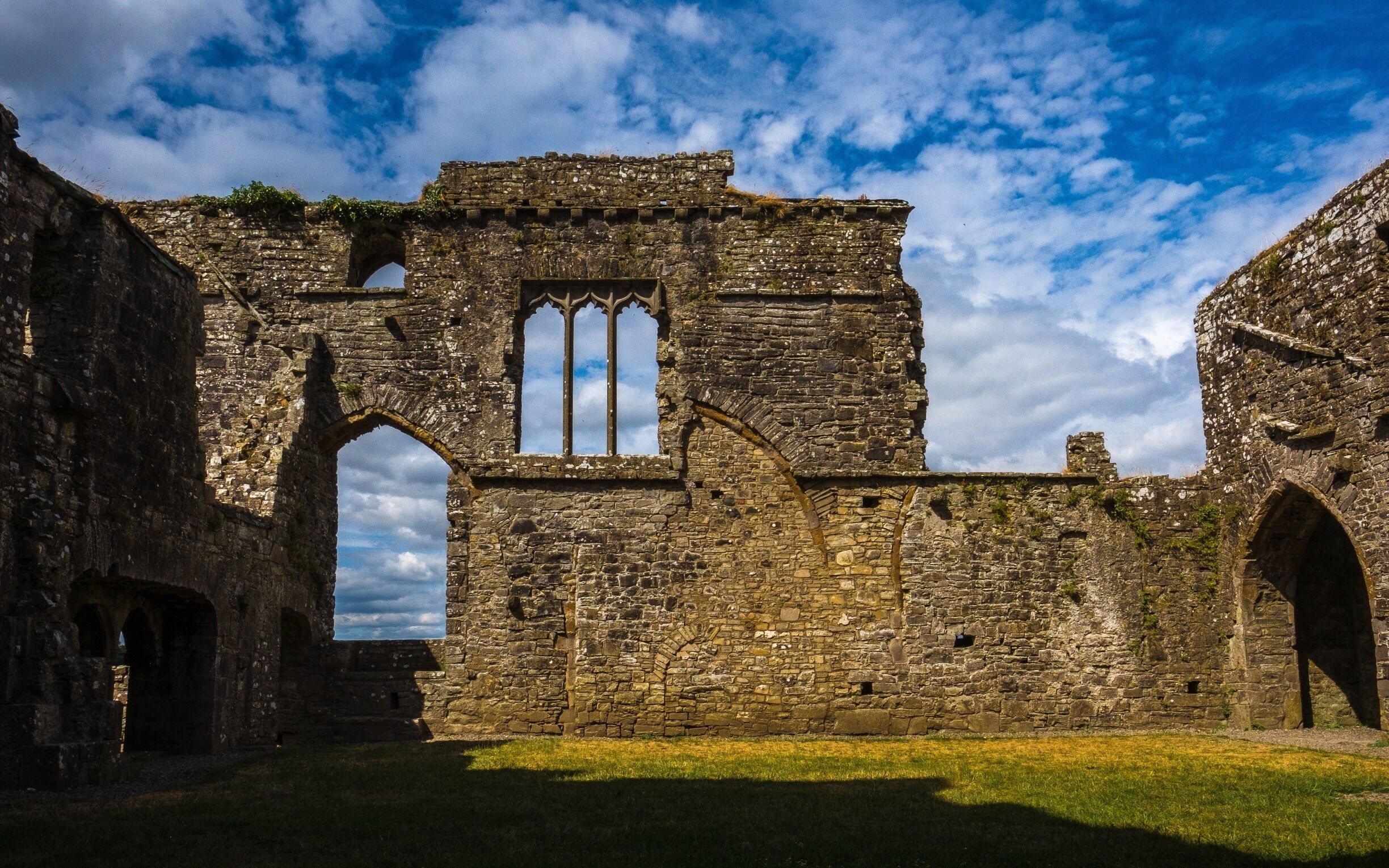 An ancient stone building with arched windows and a cross.
