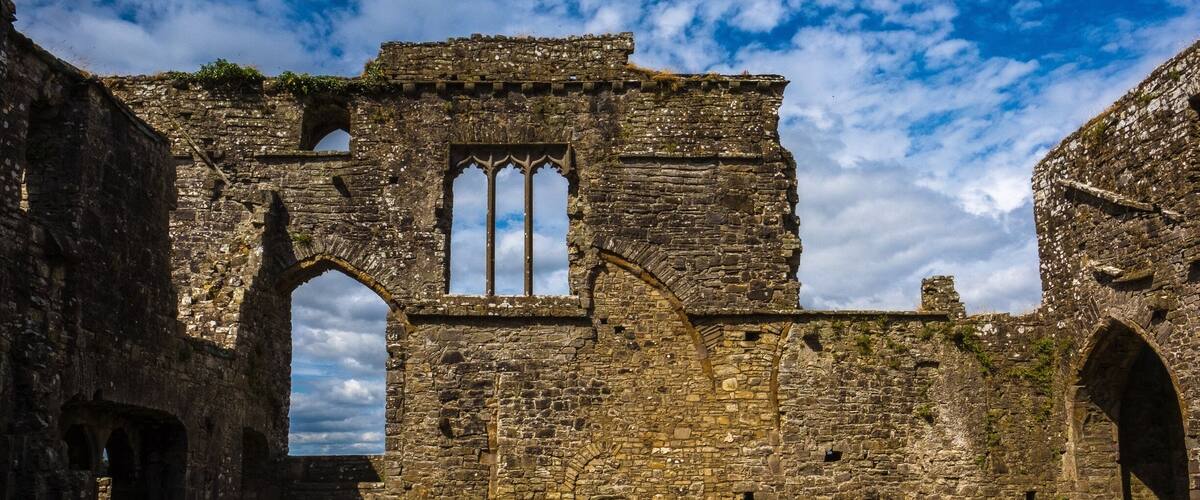 An ancient stone building with arched windows and a cross.