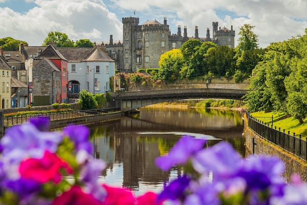 Kilkenny Castle which includes flowers, a river or creek and a small town or village