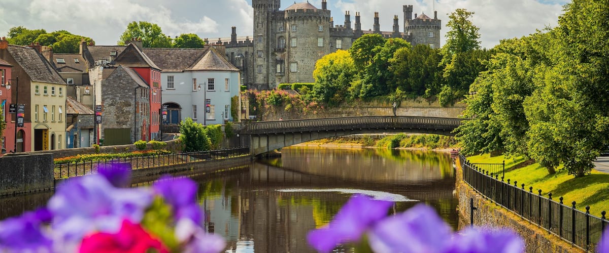 Kilkenny Castle which includes flowers, a river or creek and a small town or village