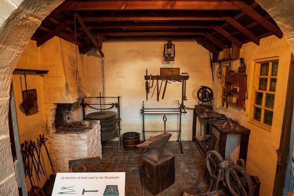 A historical blacksmith's workshop with tools, an anvil, and a forge.