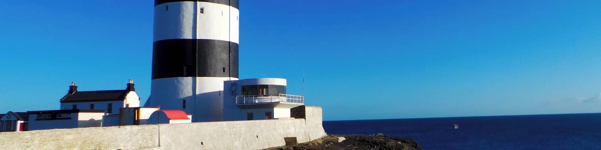 A lighthouse with a black and white striped tower, a red top, and a white base.