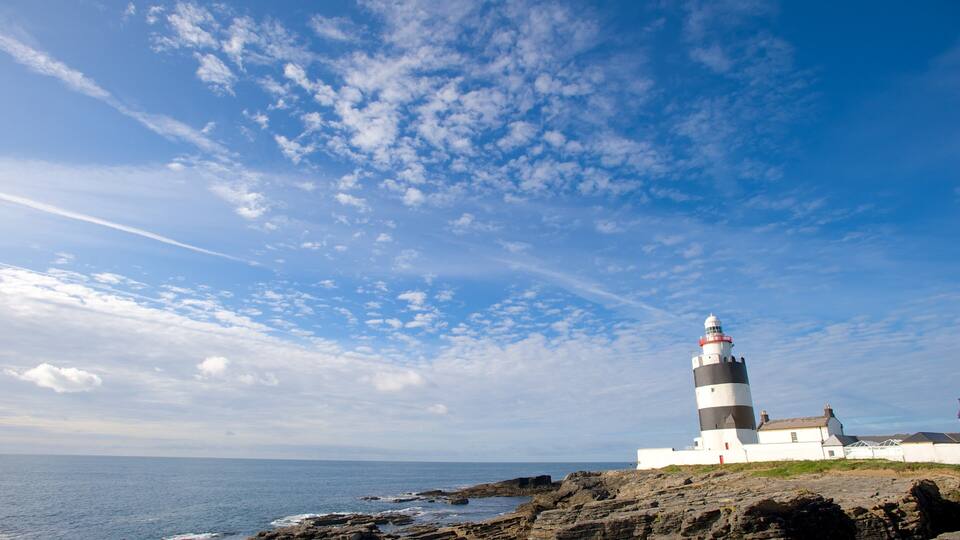 A lighthouse on a rocky coastline with a clear sky.