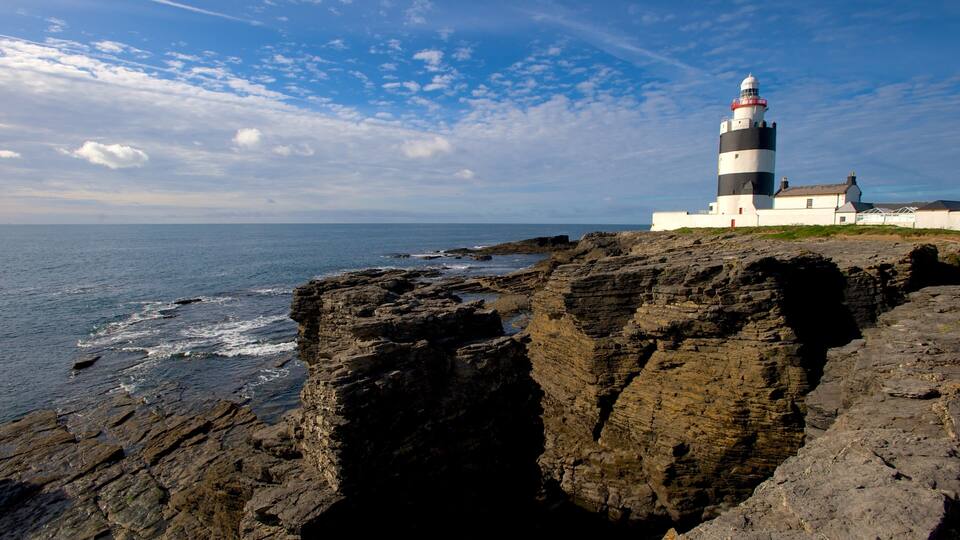 A lighthouse on a rocky cliff by the sea.