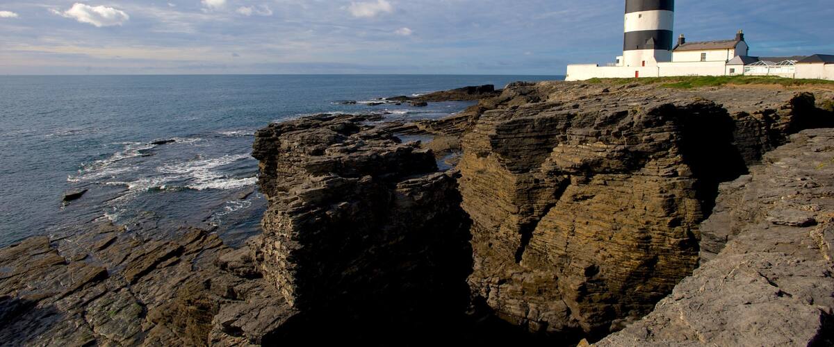 A lighthouse on a rocky cliff by the sea.