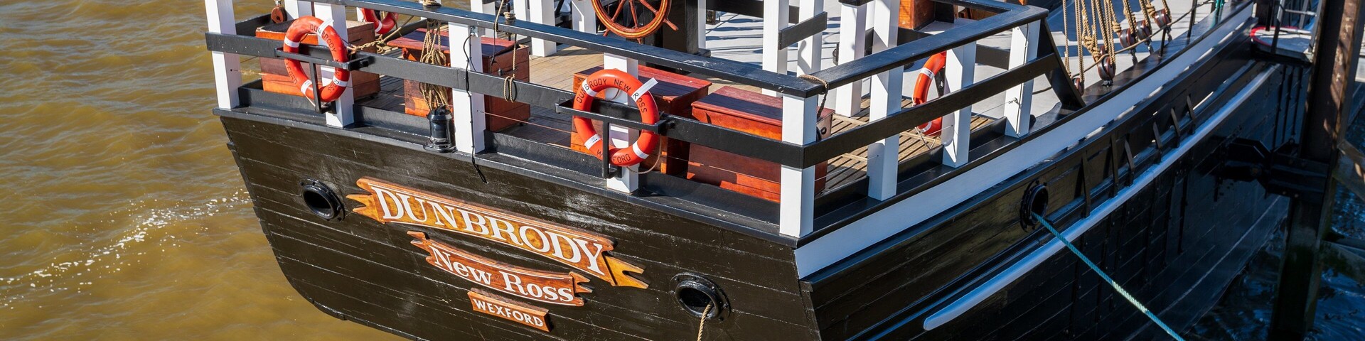 Um navio histórico chamado 'Dunbrody New Ross' atracado em um porto.
