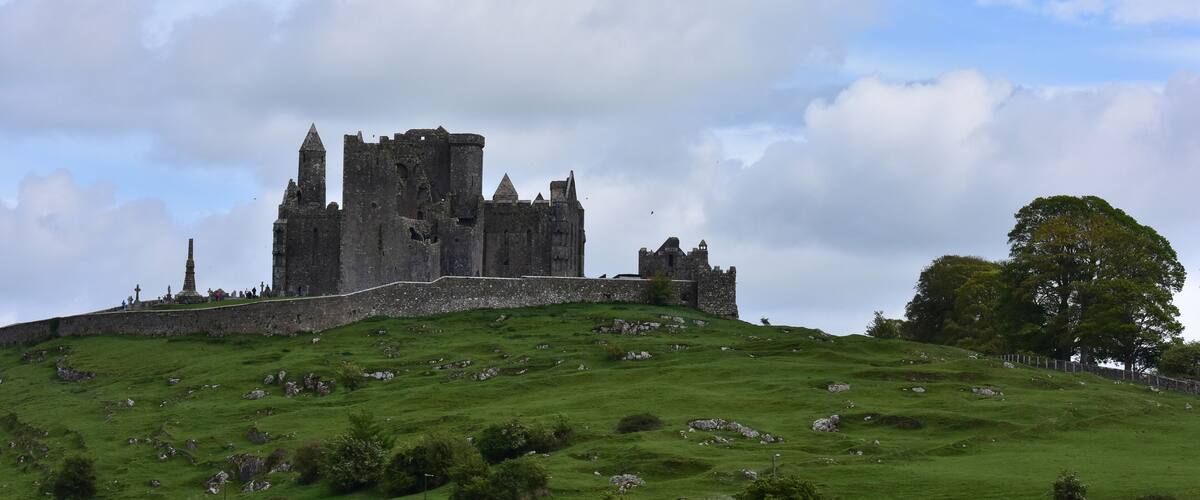 A historic castle on a grassy hill with a clear sky.