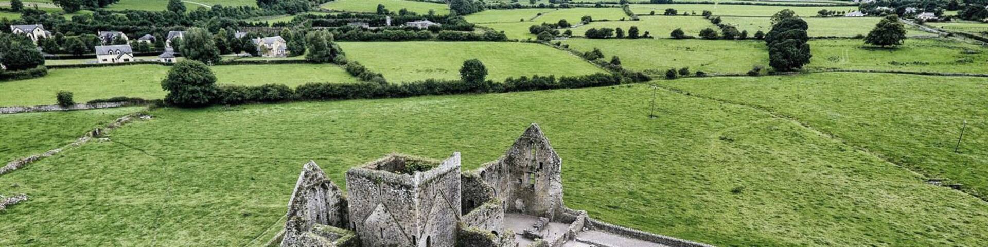 Une vue aérienne d’un château historique en ruine, entouré de champs verdoyants.