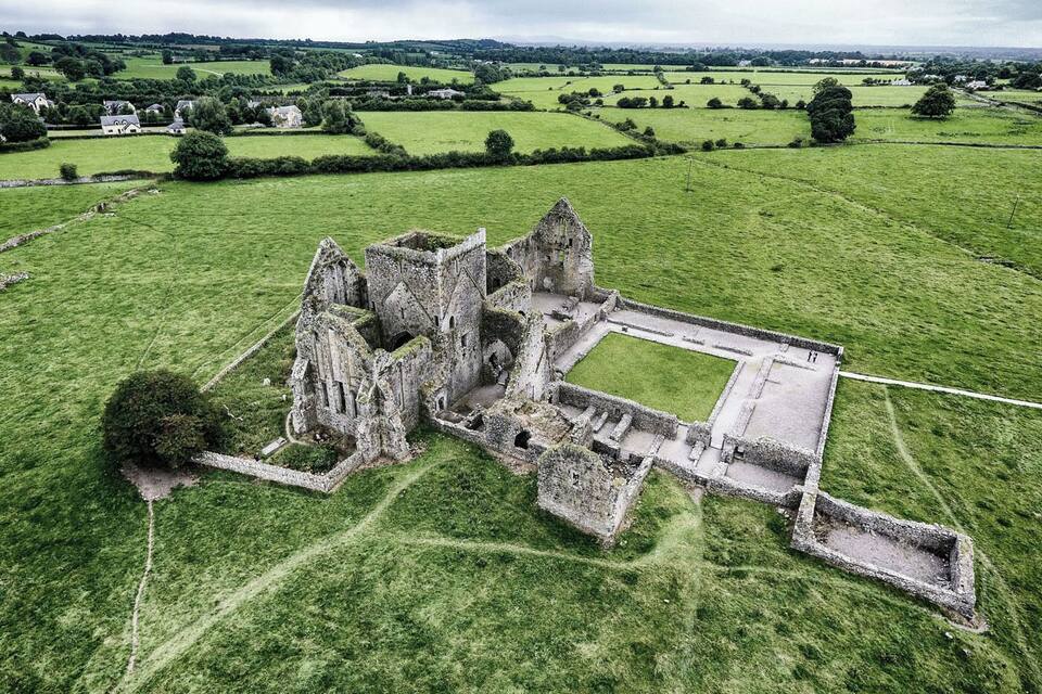 An aerial view of a historic castle ruin surrounded by lush green fields.