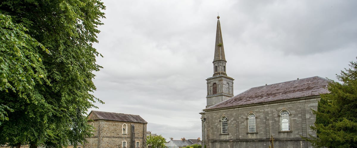 A church with a tall steeple and a graveyard in front.