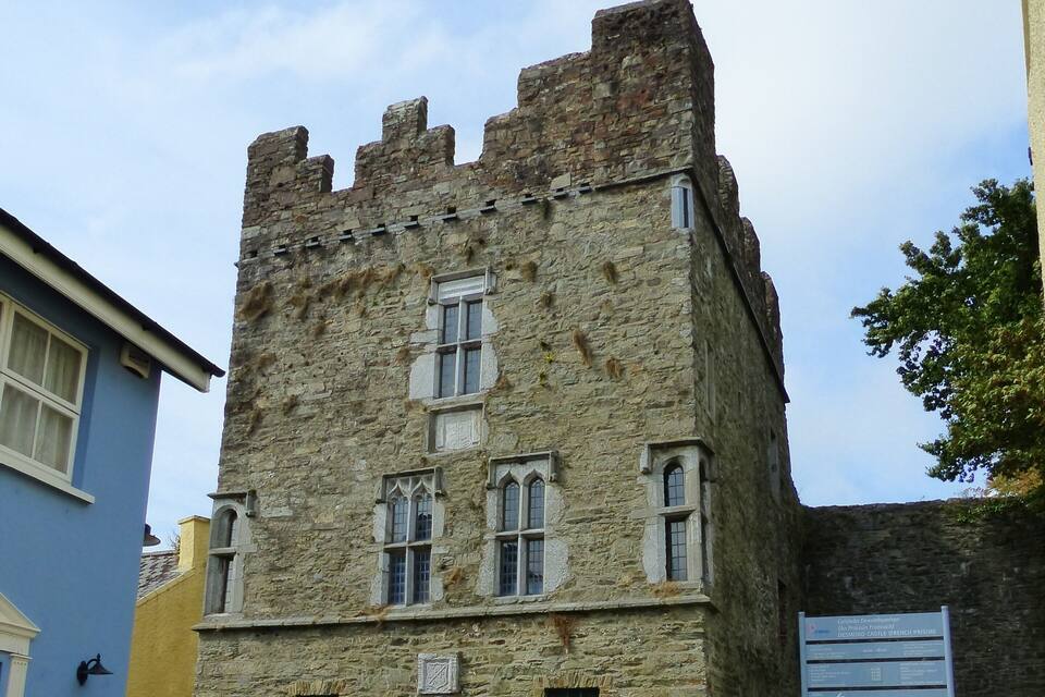 Un bâtiment historique en pierre, doté de fenêtres en arc de cercle et d’une porte en bois.