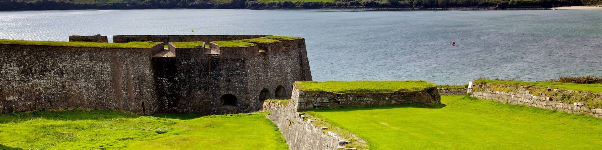 A coastal fort overlooking a green landscape and a body of water.