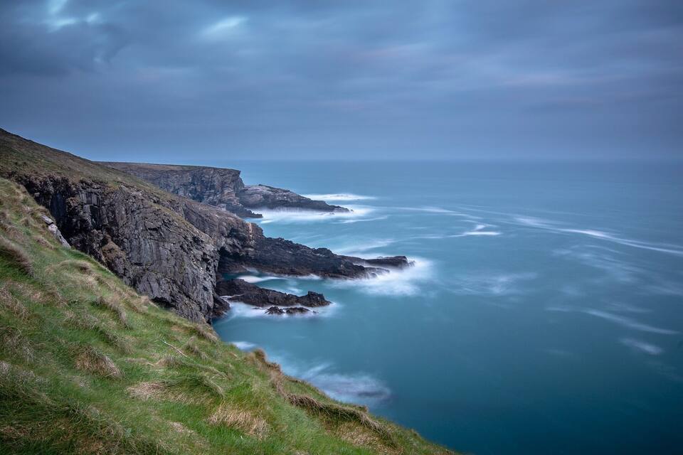 A rugged coastline with steep cliffs and a turbulent sea.