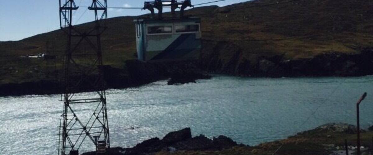 A cable car system over a body of water with a van and a truck on the ground.