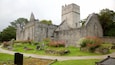An old stone church with a tower and a graveyard with flowers.