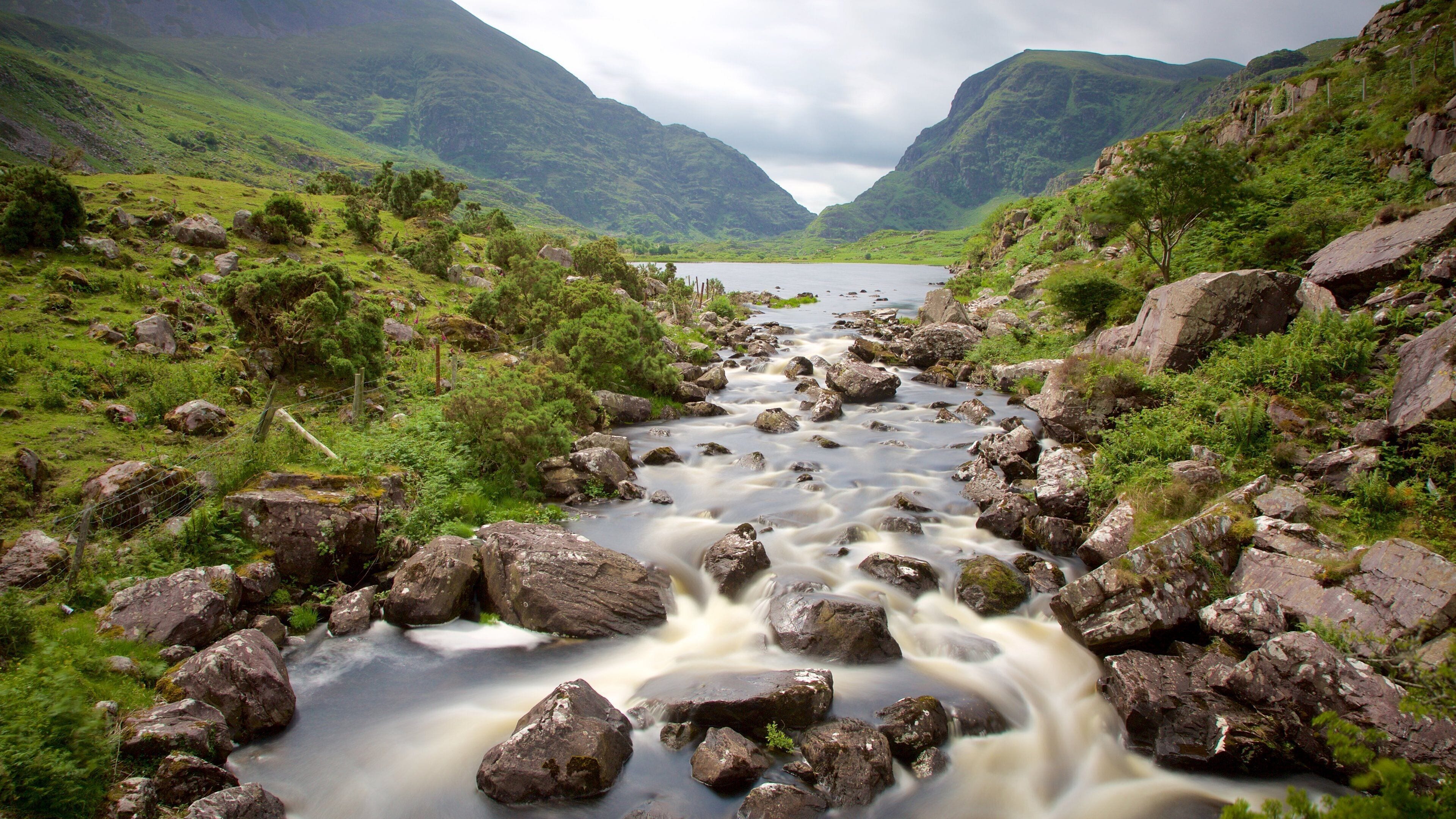 A river flowing through a mountainous landscape with rocky terrain and lush greenery.