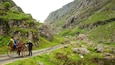 A narrow road winding through a mountainous area with rocky terrain and green vegetation.