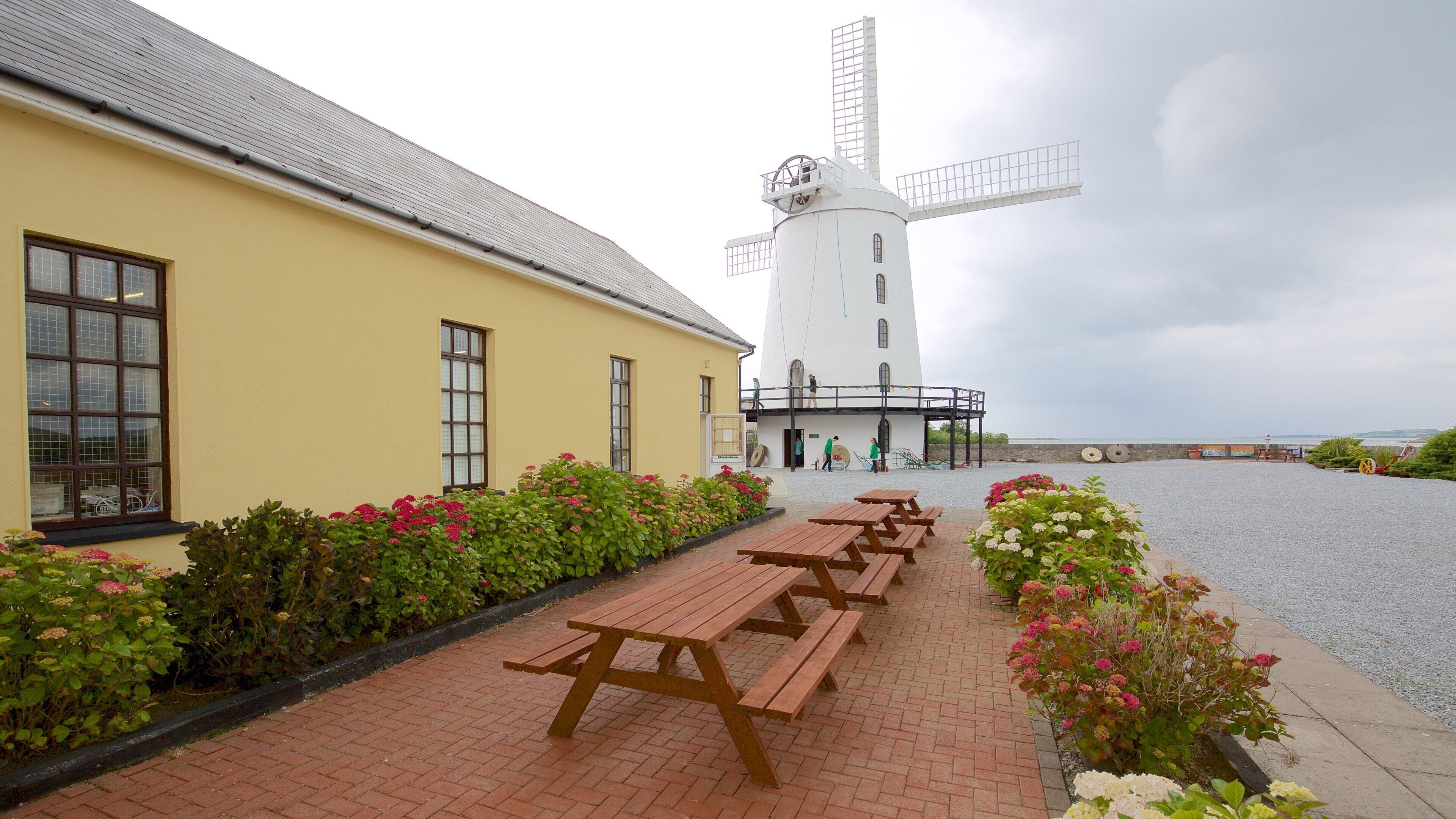 A windmill, picnic tables, and a building with a yellow facade.