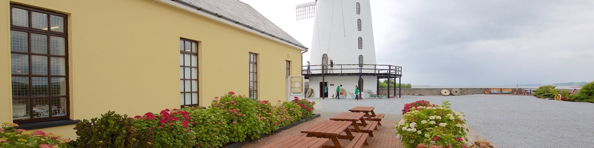 A windmill, picnic tables, and a building with a yellow facade.