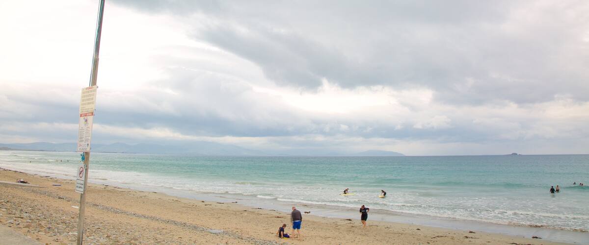 A beach with people swimming and walking.