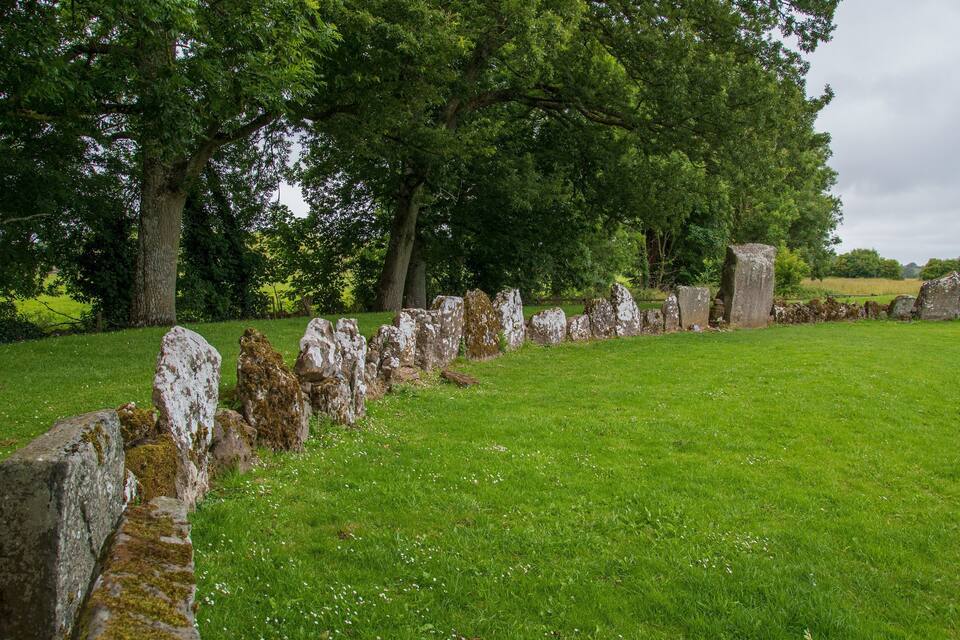 A stone circle in a grassy field with trees in the background.