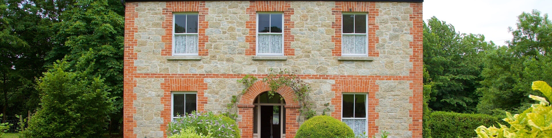 A stone house with a brick facade, a gravel driveway, and well-maintained gardens.
