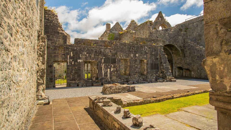 An ancient stone building with arched doorways and a grassy courtyard.