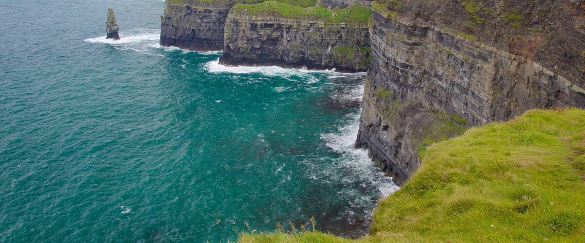 A coastal cliff with a lighthouse and grassy terrain.