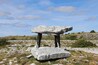 A standing stone structure in a grassy field with a clear sky.