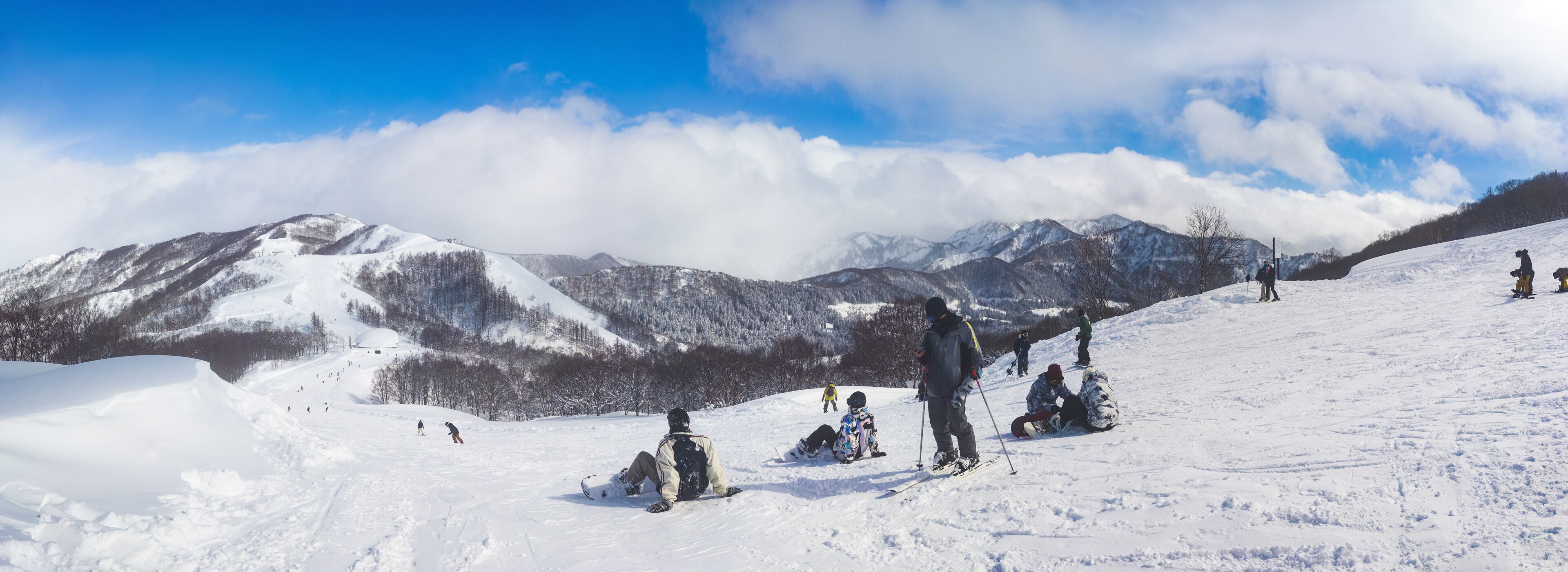 Panoramic winter landscape of a mountain ski resort with people relaxing on a slope