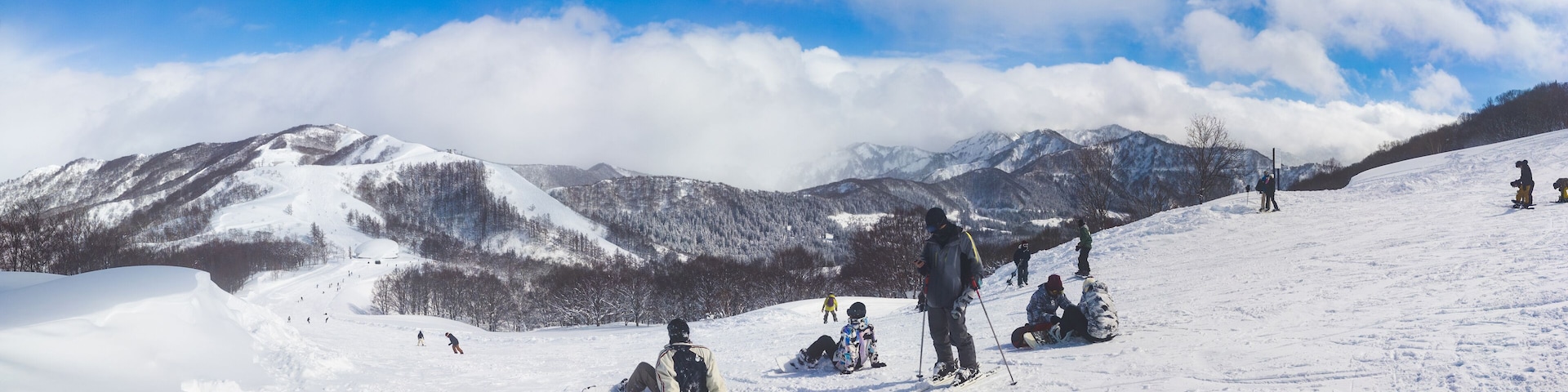 Panoramic winter landscape of a mountain ski resort with people relaxing on a slope (Maiko, Minamiuonuma, Niigata, Japan)