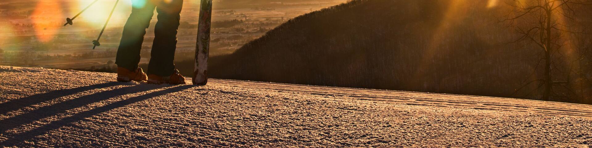 A skier stands on top of a mountain watching the sunrise in Pennsylvania.
