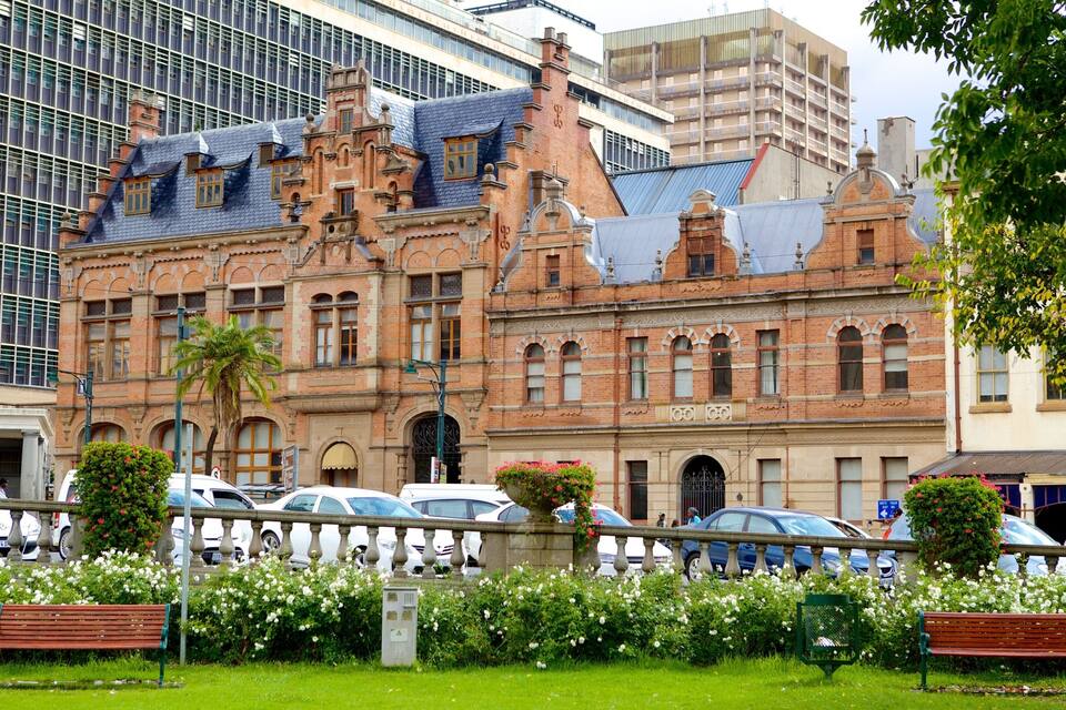 A historic building with ornate architecture, surrounded by modern buildings and parked cars.