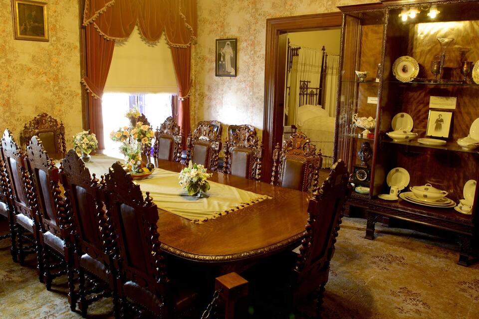 A formal dining room with a long wooden table, ornate chairs, and a china cabinet.