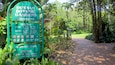 A sign for Durban Botanic Gardens with opening hours and a pathway leading into the garden.