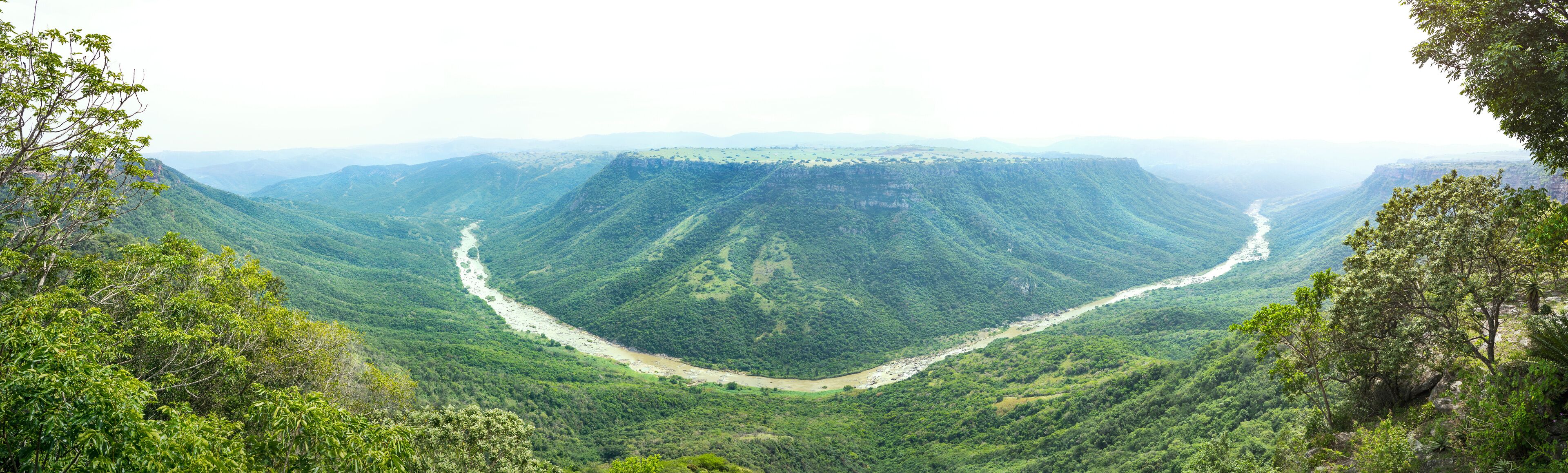 A river winding through a lush valley surrounded by steep hills.