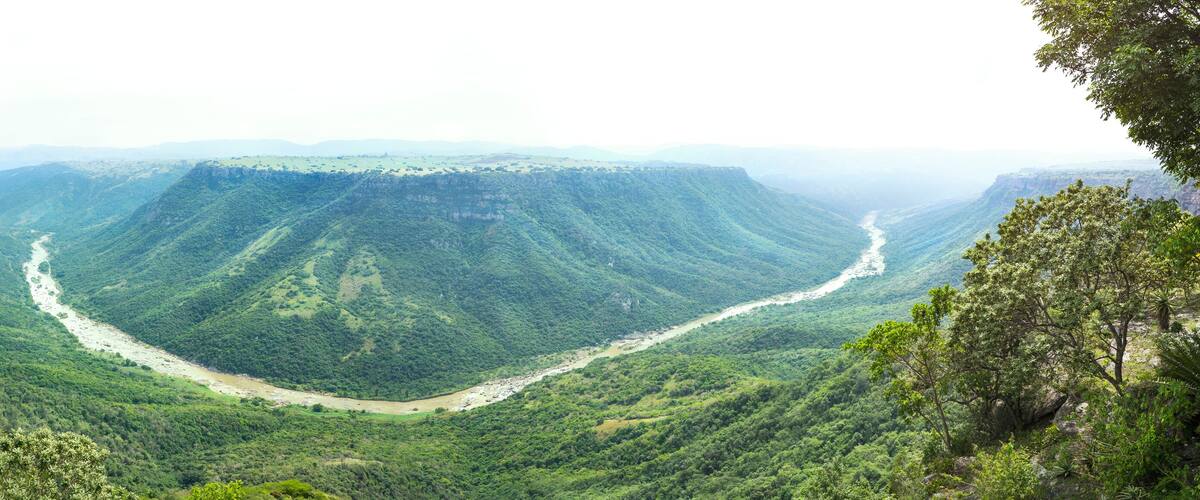 A river winding through a lush valley surrounded by steep hills.