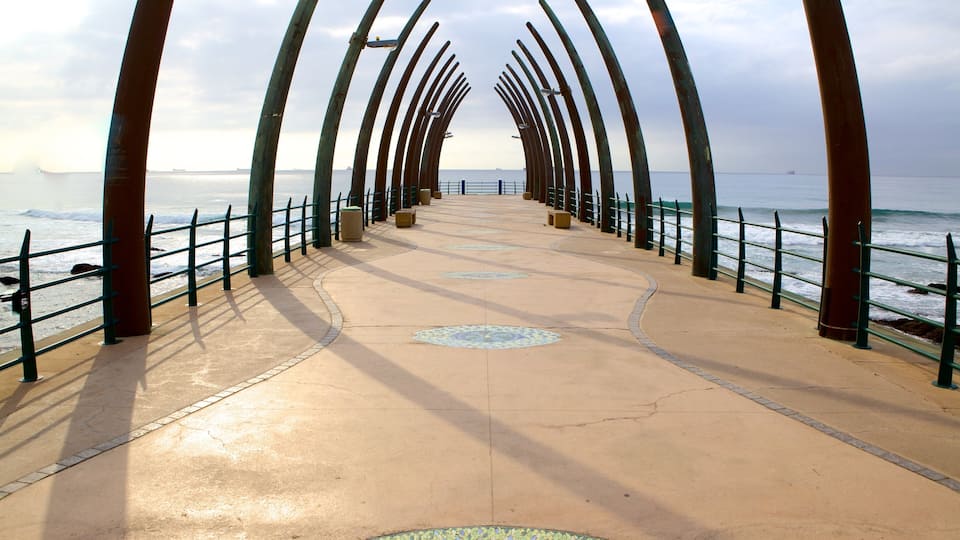 A coastal walkway with a series of arches and a patterned pavement.
