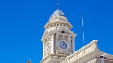 Une tour de l’horloge surmontée d’une girouette, se dressant sur un ciel bleu dégagé.