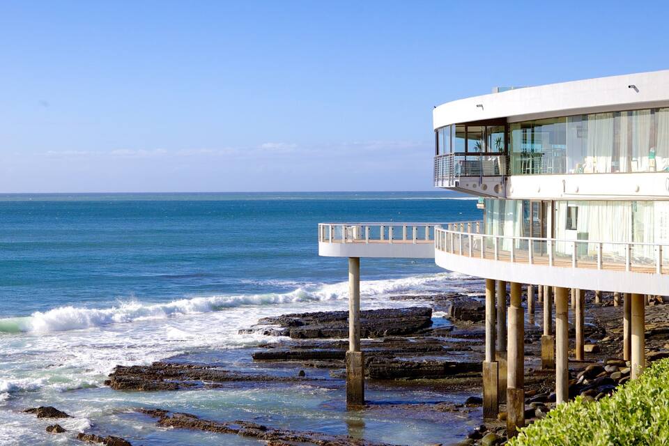 Um edifício costeiro com varanda com vista para o oceano.