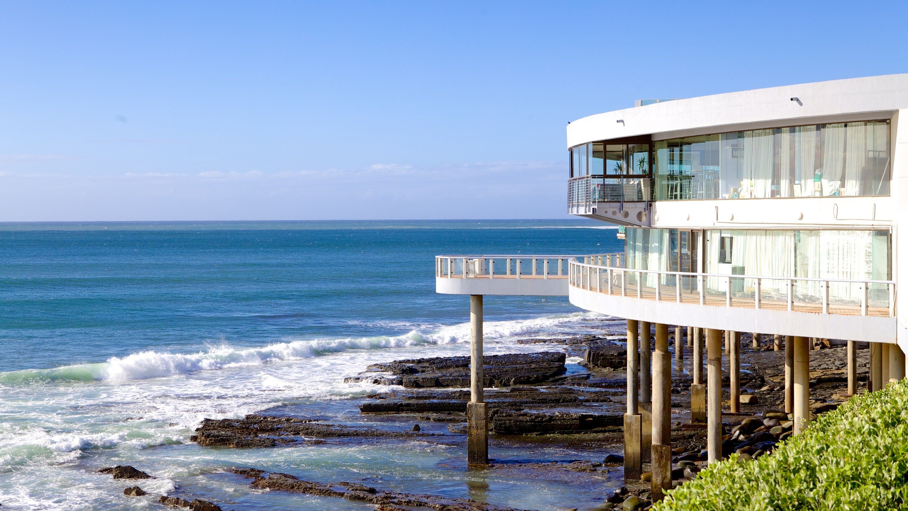 A coastal building with a balcony overlooking the ocean.