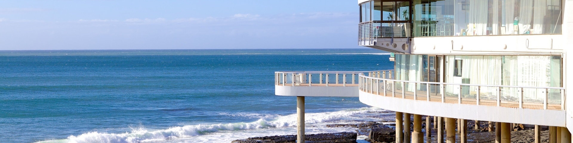 A coastal building with a balcony overlooking the ocean.