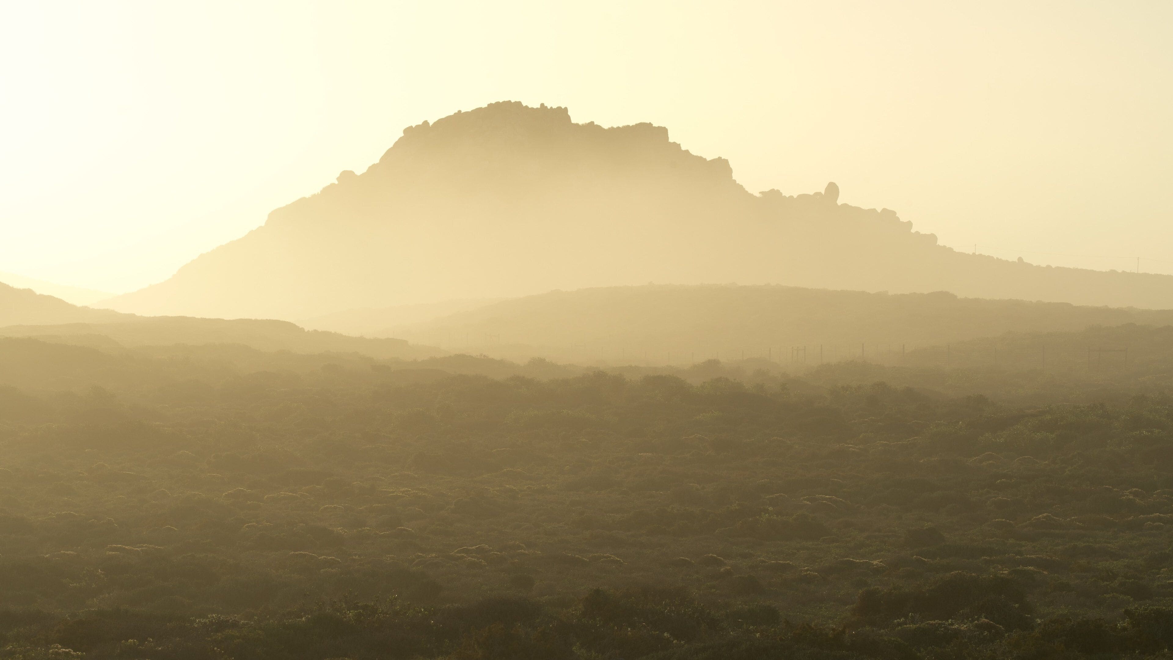 A hazy mountain range with a prominent peak in the center.