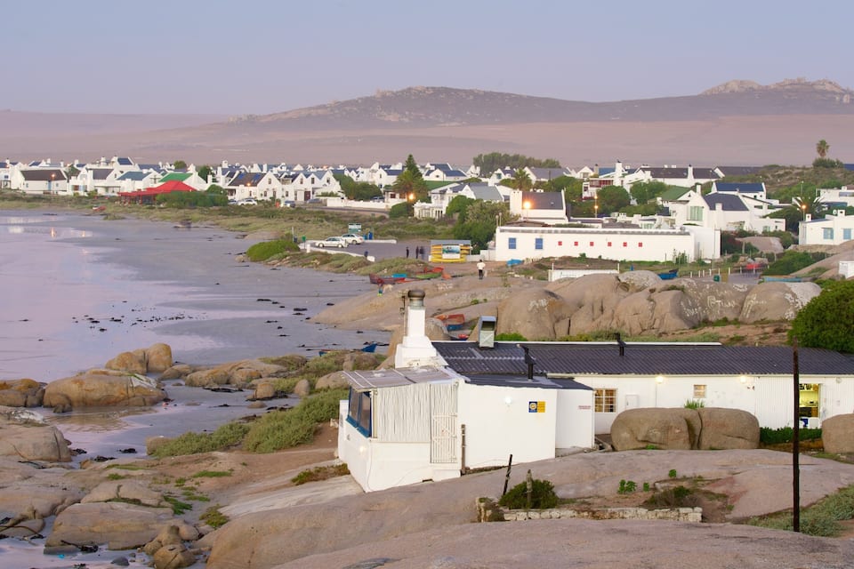 Un pueblo costero con casas blancas, un litoral rocoso y una montaña al fondo.