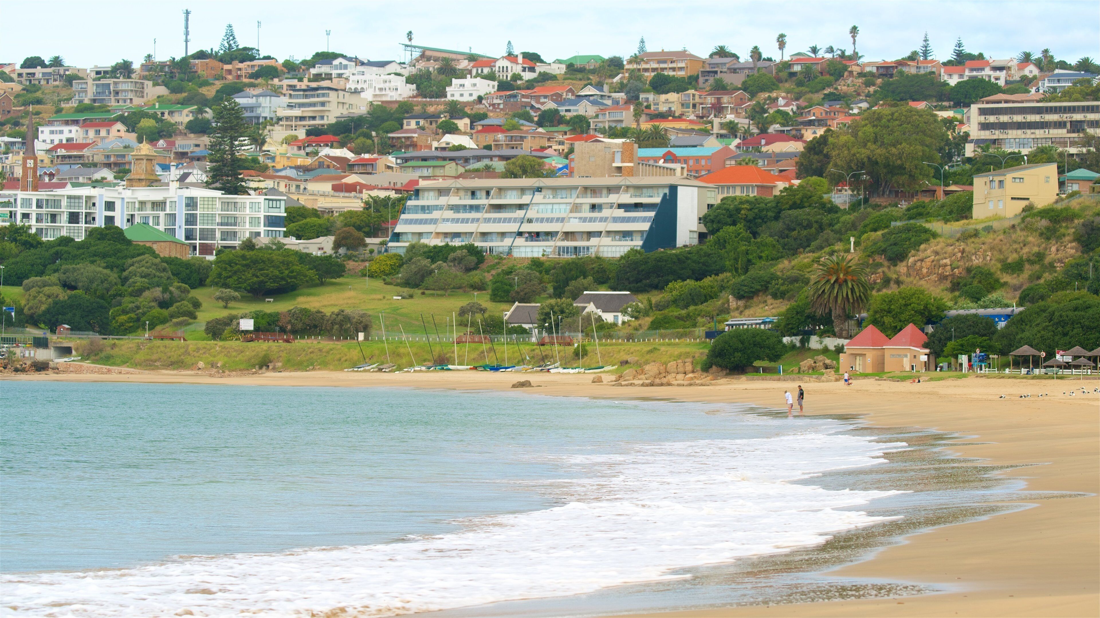 A coastal town with a beach, boats, and residential buildings.