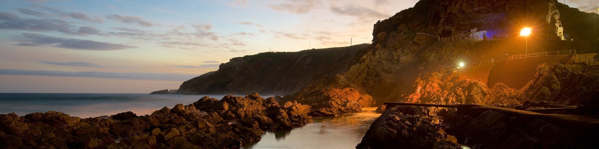 St. Blaize Lighthouse que incluye un faro, un atardecer y litoral rocoso
