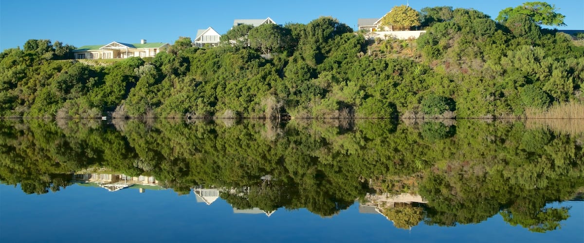 A serene lake with a reflection of houses and trees.